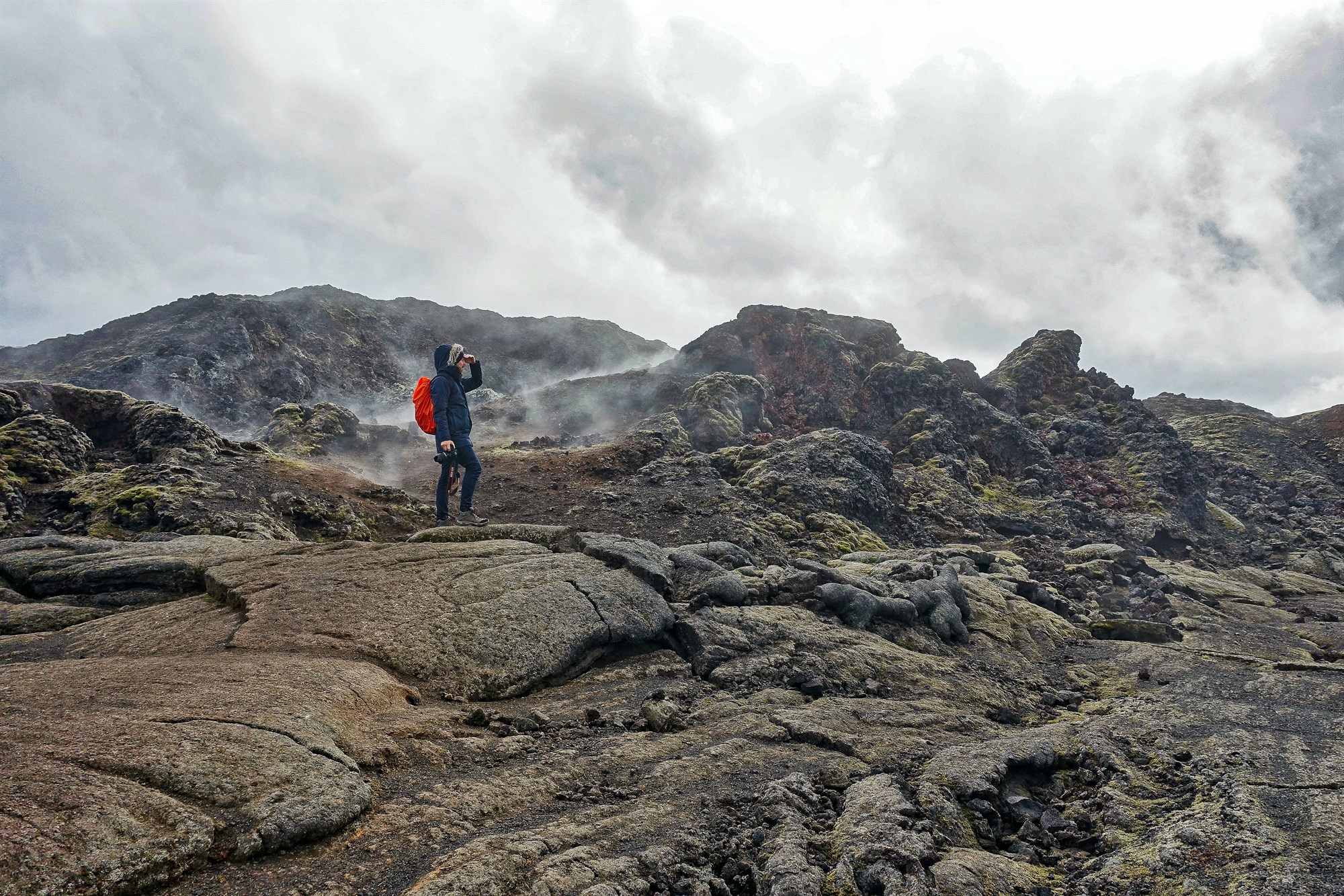 Person exploring volcanic landscape and rock formations at Krafla volcano in Iceland