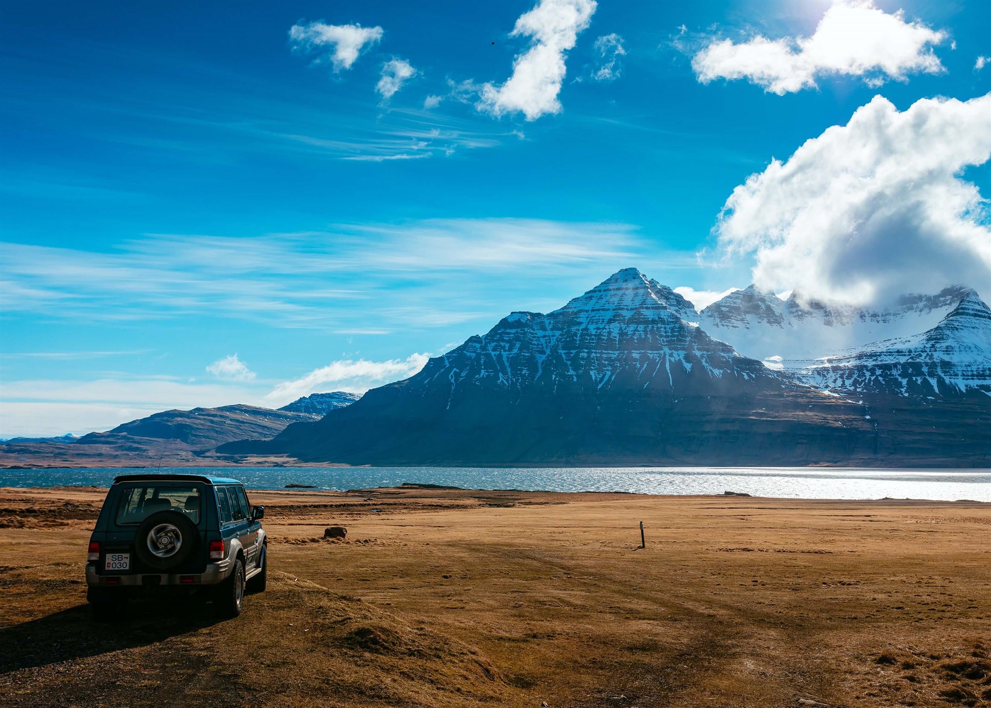 Jeep overlooking river and snow-covered mountains in Iceland