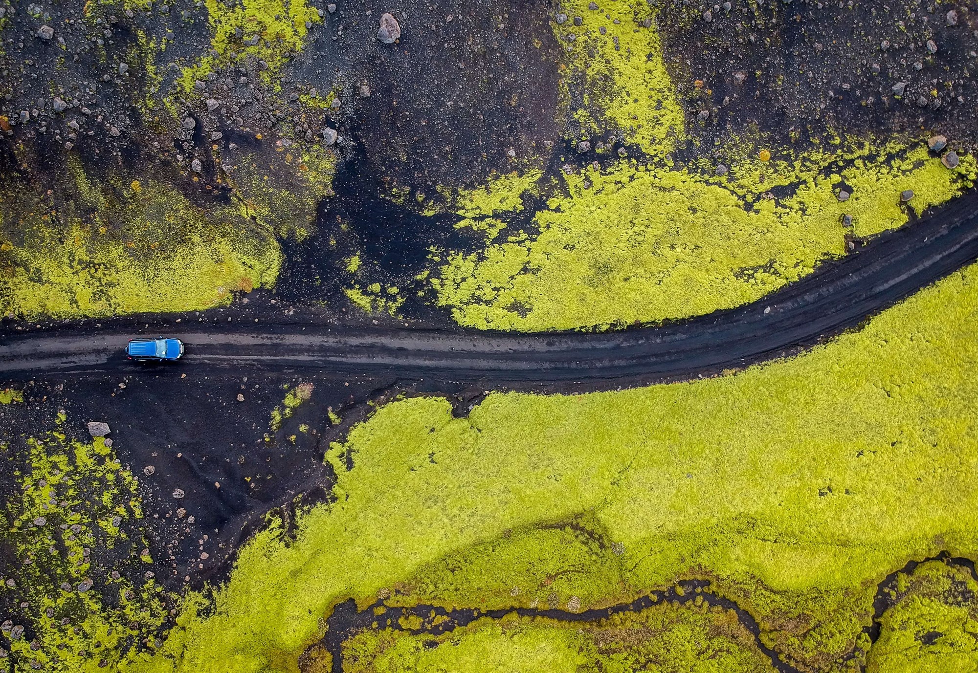 Birds-eye view of a car driving along a dirt track in Iceland